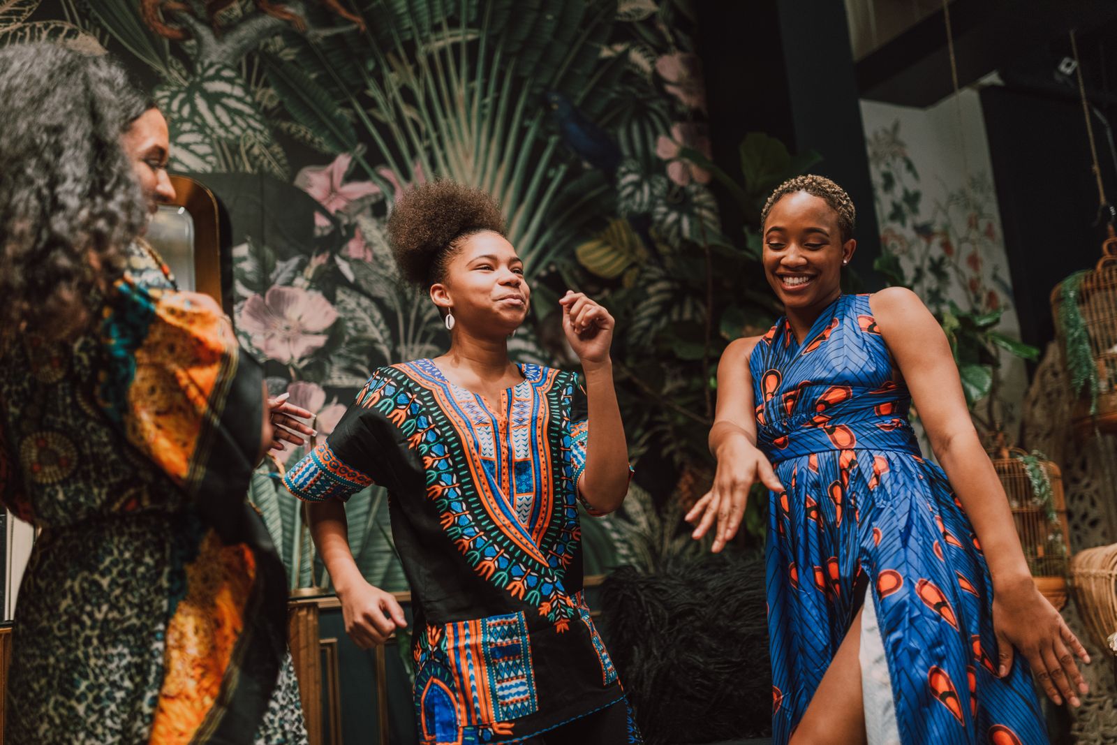 Black women joyfully dancing together in vibrant African attire